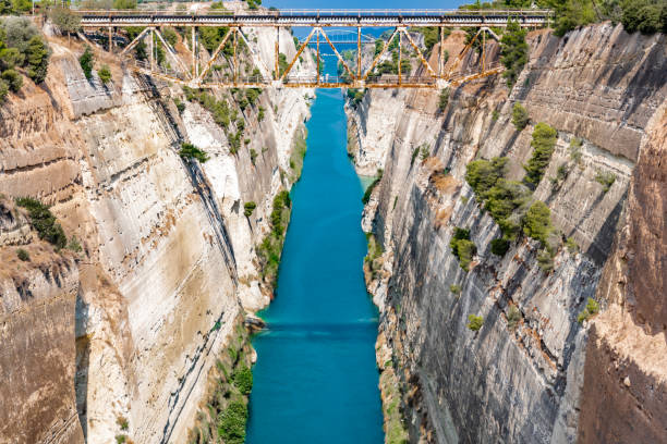 The morning sun is reflected in the blue waters of the Corinth Canal, framed by high and steep walls.