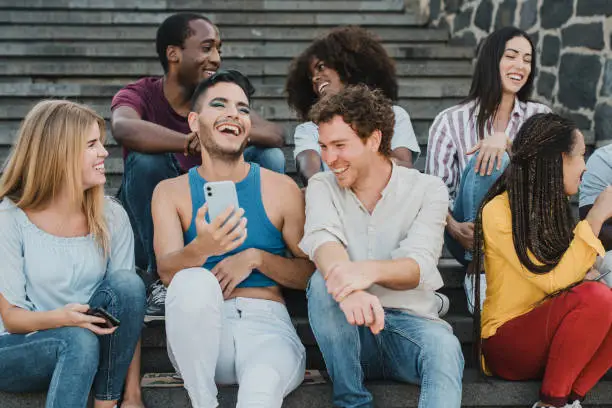 Young friends having fun using mobile phones outdoor in the city - Focus on gay man face