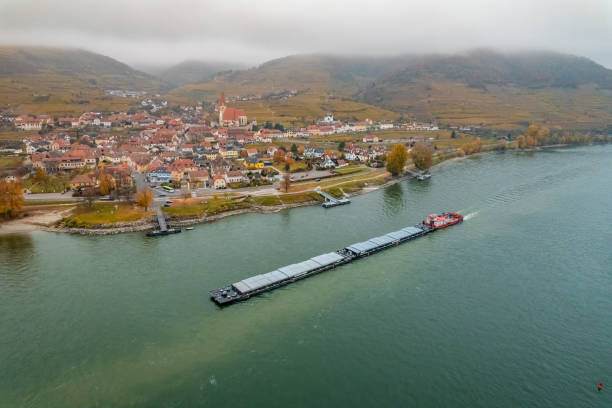 A pusher boat transporting cargo along the inland waterways of Europe on the River Danube, a vital shipping route to transport cargo and goods across the continent.