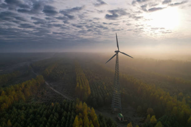 One wind turbine with a fixed propeller in a wooded area. Windless weather on a picturesque foggy morning. Renewable resource. Aerial view. Concept of alternative energy.