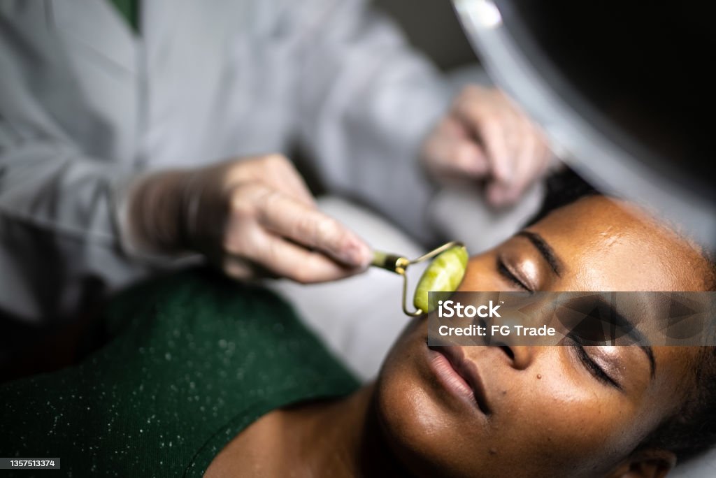 Young woman receiving a facial massage at a spa Jade Roller Stock Photo