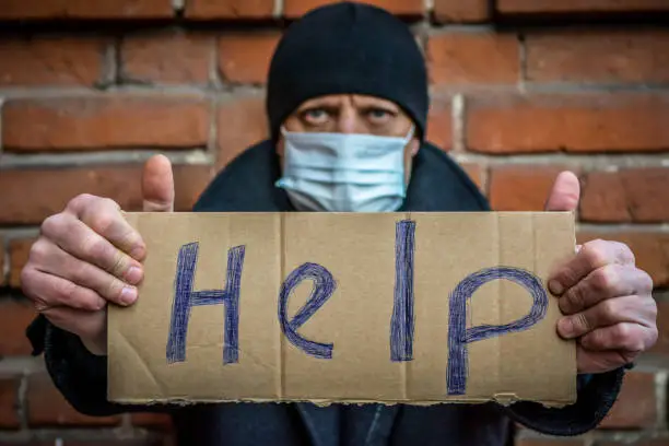 Photo of A man with a sign in his hands asks for help.