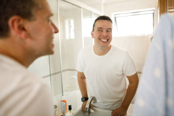 istock Man smiling checking his teeth in front of the mirror 1357515195