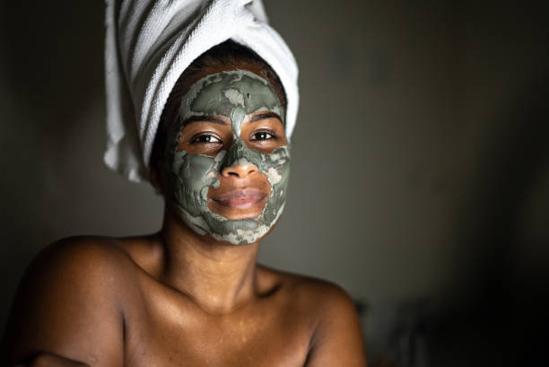 Portrait of a young woman using a facial mask Portrait of a young woman using a facial mask green clay stock pictures, royalty-free photos & images