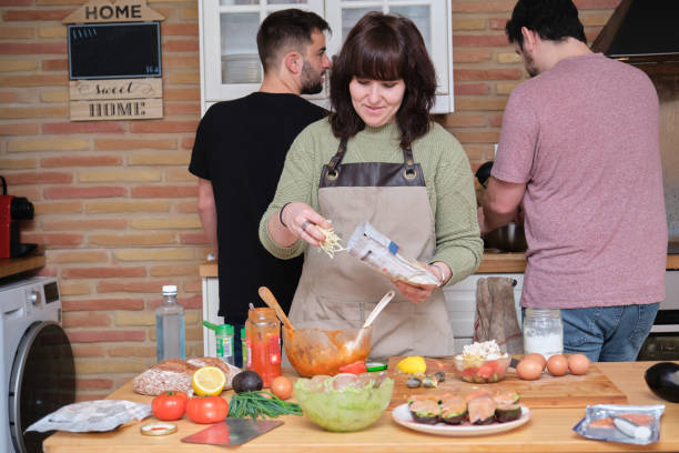 istock Group of three friends smiling, talking and cooking. 1357518729