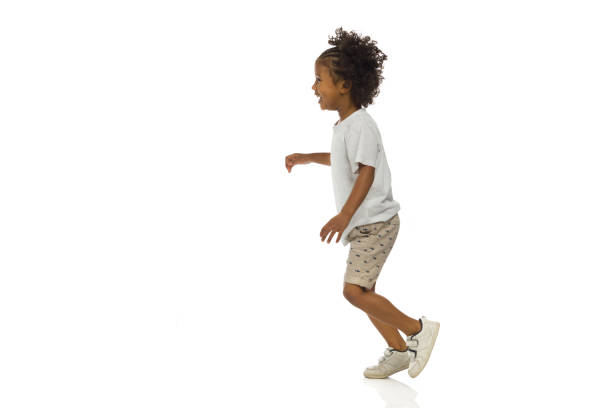 Smiling little black boy is running. Side view. Full length, isolated. stock photo