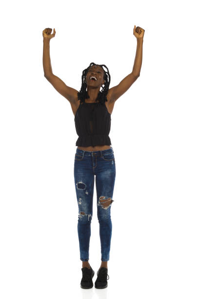 Excited and happy black woman is standing with arms raised and shouting. Full length, front view. stock photo