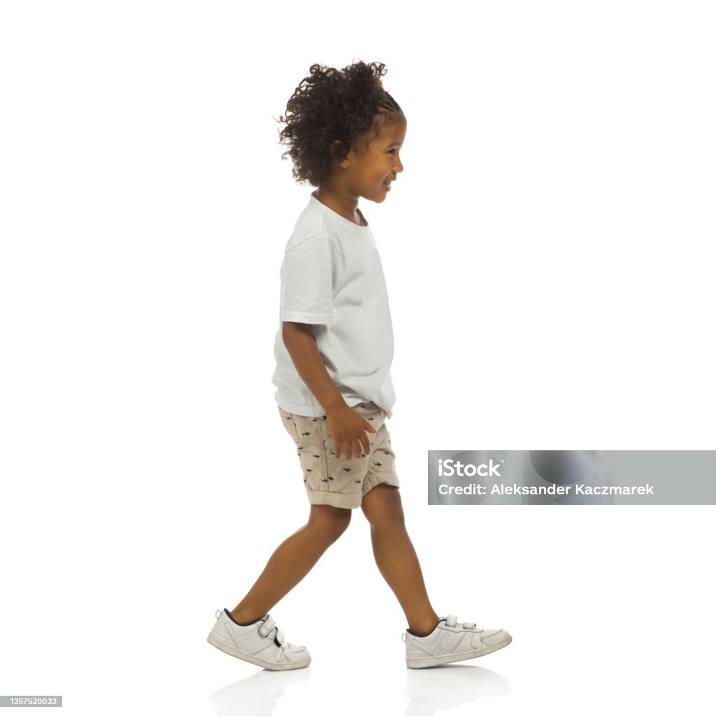 Sneaking little black boy. Side view. Full length, isolated. Sneaking happy little black boy. Side view. Full length studio shot isolated on white. Child Stock Photo