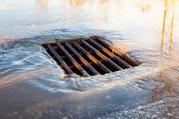 雨の後の都市の下水道。道路上の嵐の下水道 それは春です - マンホール ストックフォトと画像