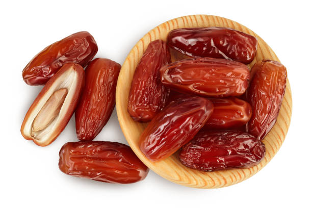 istock Dates in wooden bowl isolated on white background with clipping path. Top view. Flat lay 1357520215