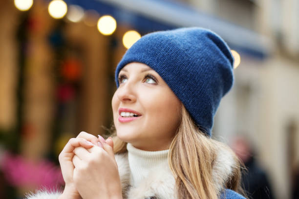 une jeune fille en foulard et chapeau se réchauffe les mains en se promenant dans la ville de noël. - christmas fashion model human arm beautiful photos et images de collection