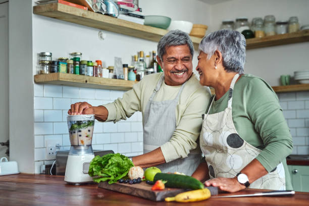 zdjęcie starszej pary przygotowującej zdrowy koktajl w kuchni w domu - senior adult senior couple happiness couple zdjęcia i obrazy z banku zdjęć