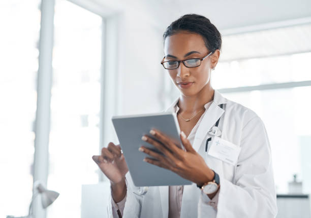 scatto di un giovane medico che usa il suo tablet digitale al lavoro - lab coat women one person female foto e immagini stock