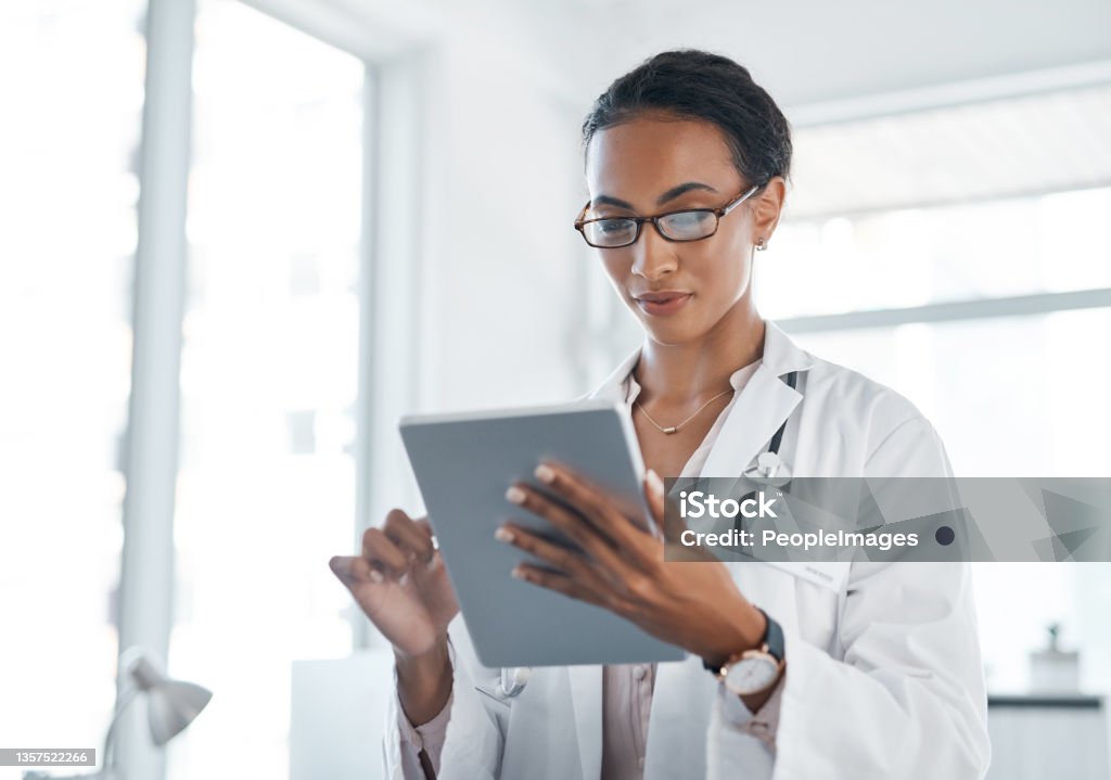 Shot of a young doctor using her digital tablet at work Getting information on the go Doctor Stock Photo