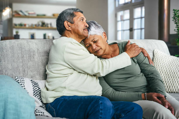 scatto di un uomo anziano che sostiene sua moglie durante un momento difficile a casa - senior women depression sadness women foto e immagini stock