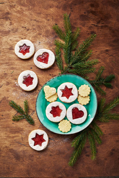 klassische linzer weihnachtsplätzchen mit himbeer- oder erdbeermarmelade auf holztisch - cookie heart shape shortbread christmas stock-fotos und bilder