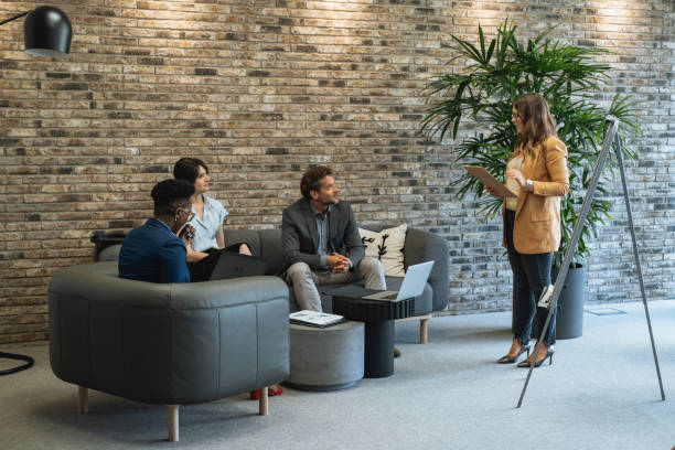 Happy multiracial group of business peoples in a casual meeting at their company listening to female colleague speech.