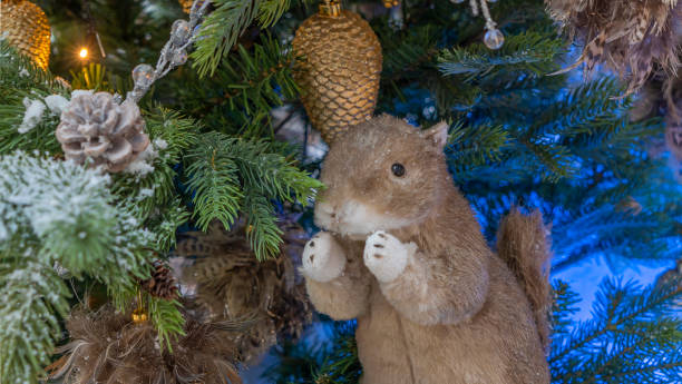 Toy squirrel or gopher sitting on a fluffy fir branches. Merry Christmas and Happy New Year Greeting Card Design. The concept of New Year and Christmas. Festive decoration.