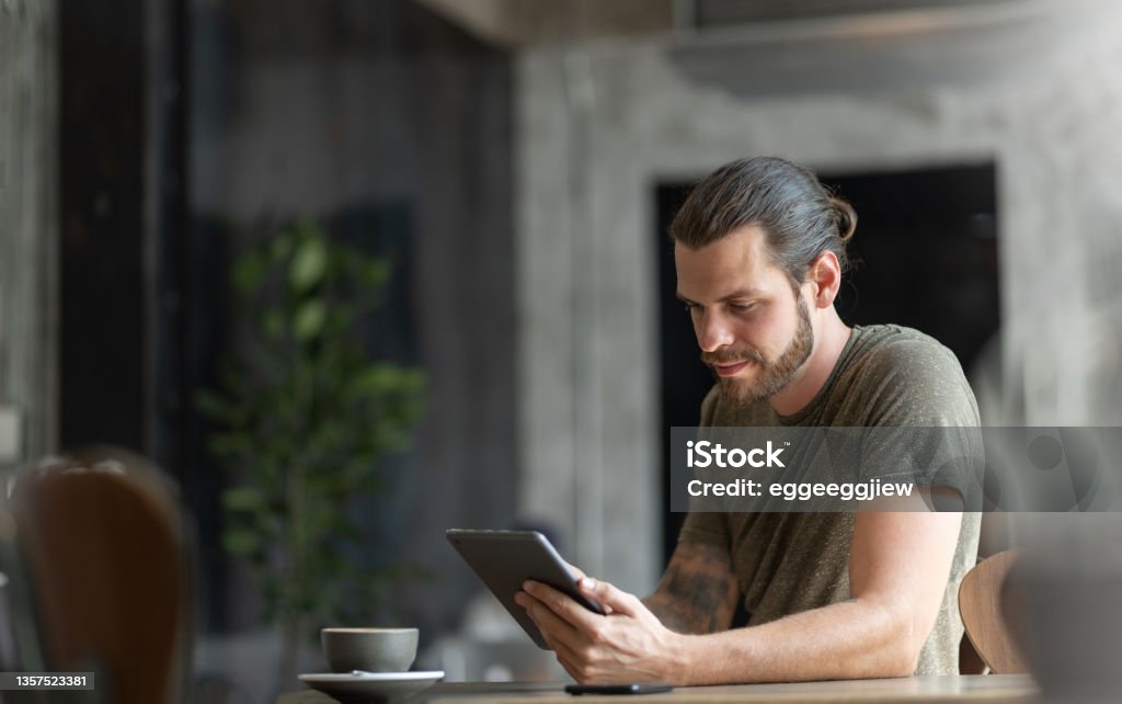Attractive Beard man sitting using digital tablet Attractive Beard man sitting using digital tablet at the coffee shop. Men Stock Photo