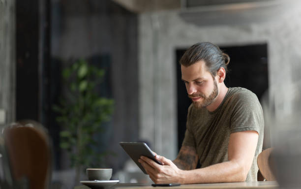 Attractive Beard man sitting using digital tablet Attractive Beard man sitting using digital tablet at the coffee shop. cafe tablet stock pictures, royalty-free photos & images