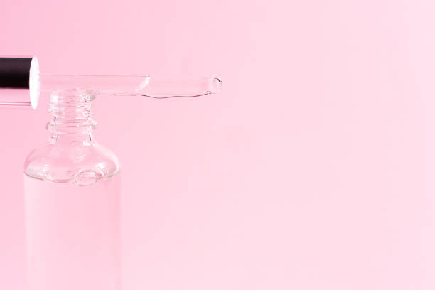 istock Glass jar with serum and pipette on pink background 1357523421