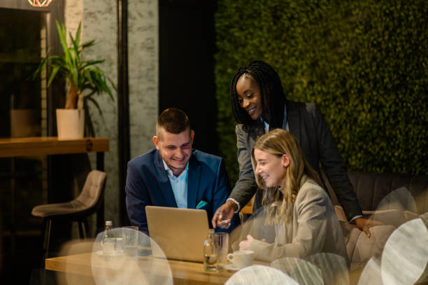 istock Cheerful work colleagues working on a laptop while having a meeting in a cafe 1357523471