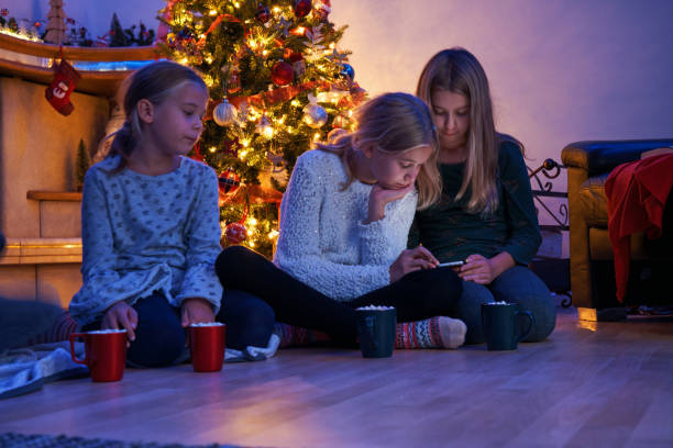 istock Little Kids Sitting in Front of Christmas Tree Reading and Having Fun 1357523741