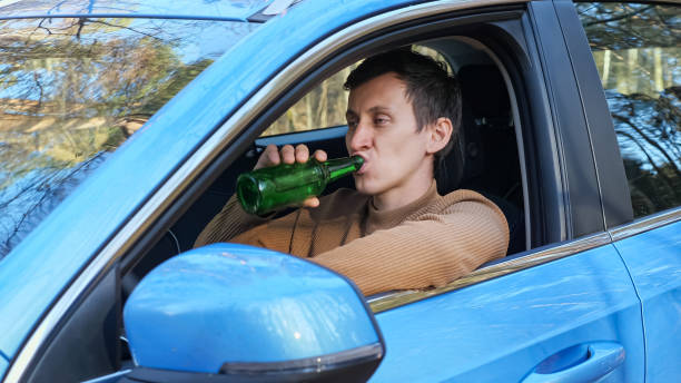istock Driver drinks alcohol from bottle in car cabin after work 1357523952