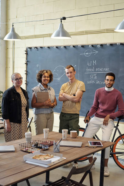 istock Happy young economists standing by table in large openspace office 1357524732