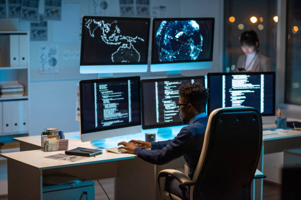 joven gerente de seguridad cibernética contemporáneo escribiendo frente a la computadora - cyber security fotografías e imágenes de stock