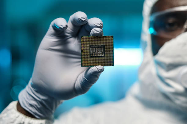 istock Gloved hand of African man holding small board with microchip 1357525245