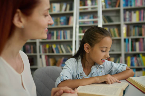 istock Girl reading book touching page with finger 1357525416
