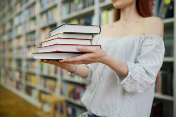 istock Woman hands holding a stack of books 1357525596