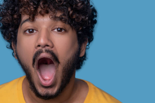istock Bearded curly-haired open-mouthed young man looking ahead 1357525791