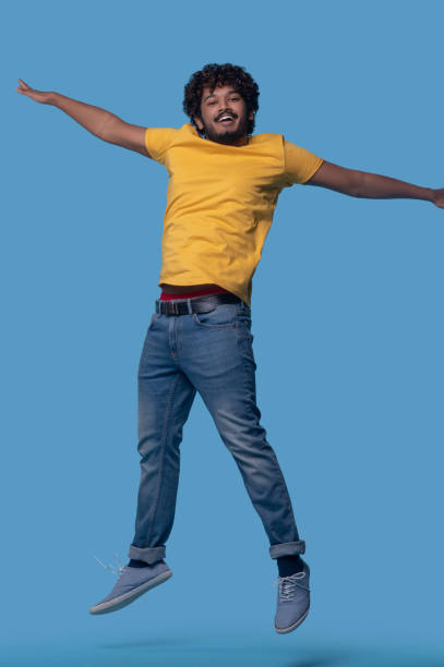 istock Cute young man with a toothy smile jumping up 1357525818