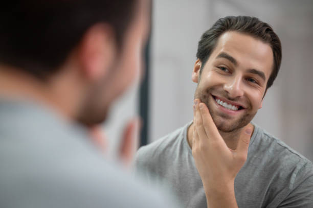 istock A young man in grey tshirt looking at his reflection in the mirror 1357526067