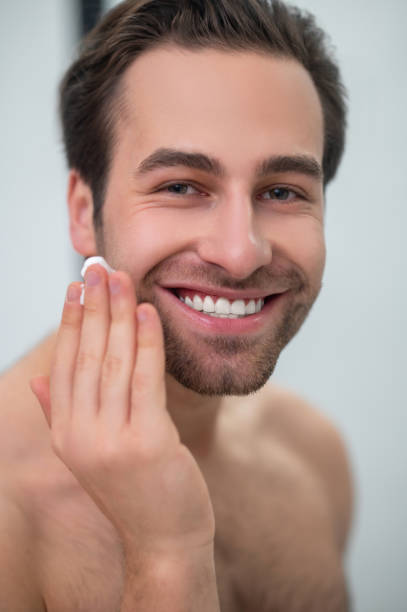 istock Smiling man cleaning his face at the mirror 1357526097