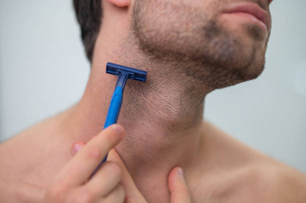 istock Young man shaving at the mirror 1357526109