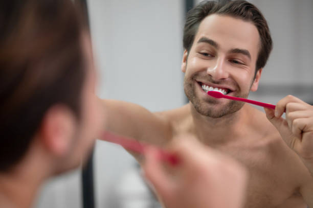 istock Smiling young man brshing his teeth and looking carefree 1357526113