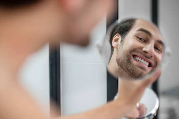 istock Young man examining his face while watching into the round mirror 1357526117