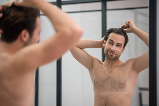 istock Dark-haired man brushing his hair at the mirror 1357526130