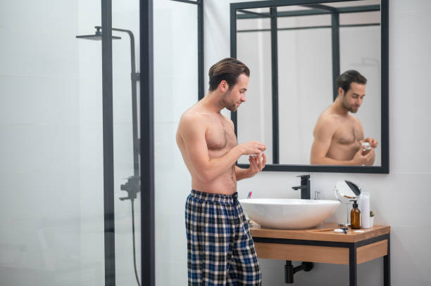 istock Man in plaid home pants standing at the mirror 1357526136