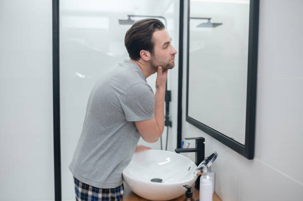 istock Dark-haired man looking at his reflection in a mirror 1357526164