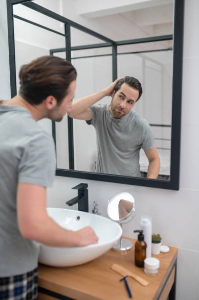 istock Man near the mirror scrutinizing himself 1357526169