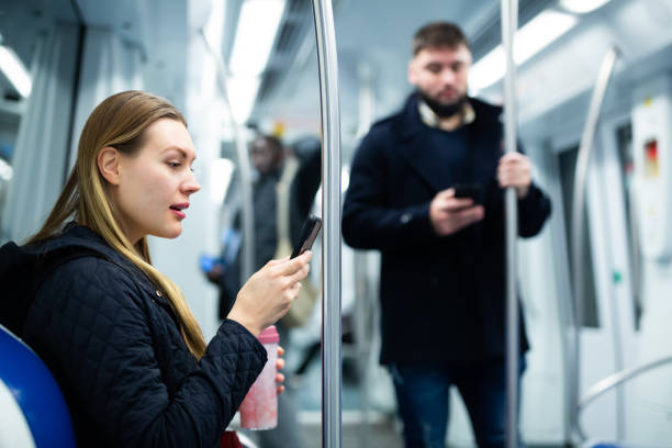 istock Young woman with phone in subway car 1357526205