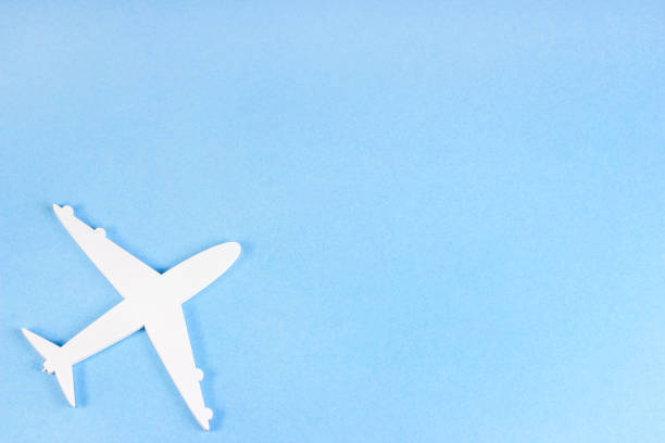 istock Top view flat lay of white plane model on light sky blue background with copy space 1357526521