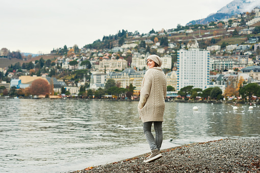 Outdoor portrait of happy young woman enjoying nice walk by lake Geneva in Montreux city, Switzerland