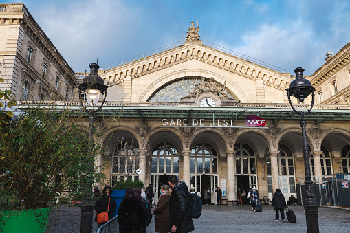 Paris, France - November 28, 2021: People stand outside the Gare de L'Est, one of several train stations in Paris.