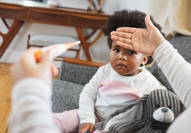 foto de una madre irreconocible comprobando la temperatura de su hija en casa - sick girl fotografías e imágenes de stock