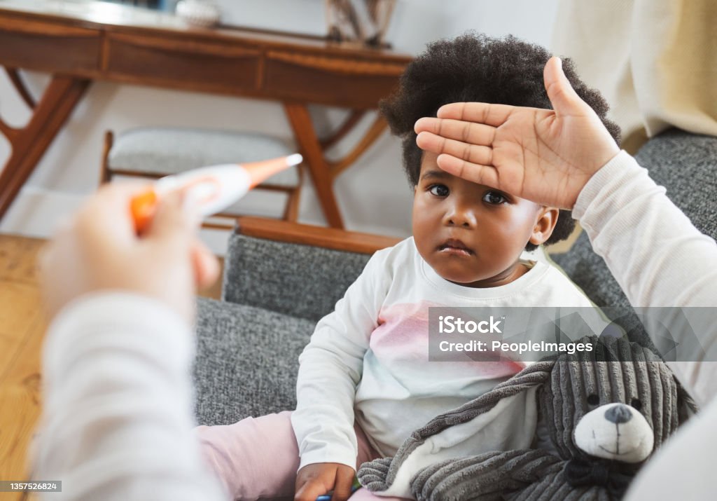 Shot of an unrecognizable mother checking her daughter's temperature at home A mother's love knows no boundaries Baby - Human Age Stock Photo